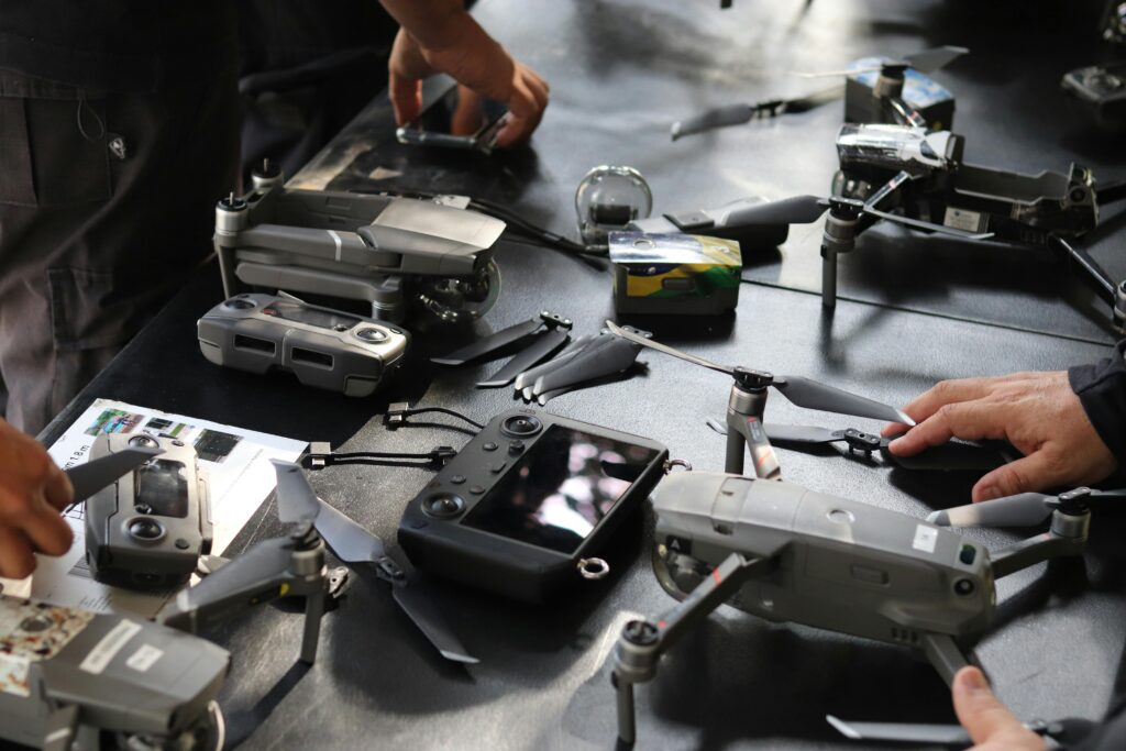 Close-up of hands setting up drones and equipment indoors, showcasing technology and teamwork.